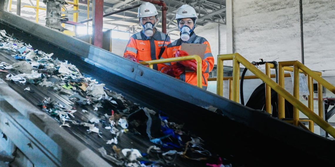 Karyawan SIG melakukan pengecekan material (Refused-Derived Fuel) yang akan dicacah untuk dimanfaatkan menjadi bahan bakar alternatif di area green zone Pabrik Narogong, Jawa Barat.