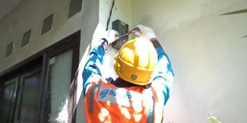 Ilustrasi Petugas PLN saat melakukan penambahan daya pada kWh meter milik pelanggan.