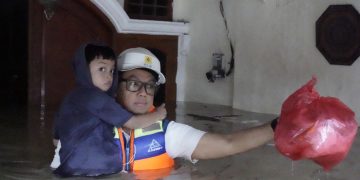 Direktur Utama PLN Prasodjo (kanan) ketika mengevakuasi seorang anak yang rumahnya terkena banjir di Perumahan Nasional 1 Kayuringin Jaya, Bekasi, Jawa Barat pada Selasa (4/3).
