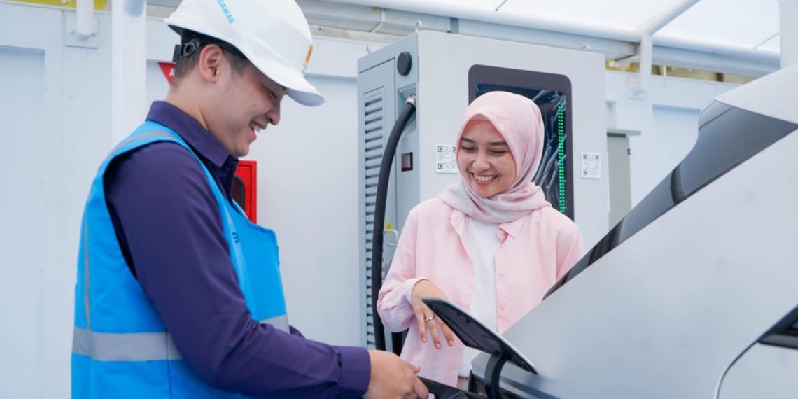Ilustrasi pengguna electric vehicle dibantu oleh Petugas PLN ketika mengisi kendaraan listriknya di SPKLU.