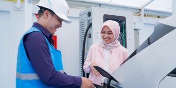 Ilustrasi pengguna electric vehicle dibantu oleh Petugas PLN ketika mengisi kendaraan listriknya di SPKLU.