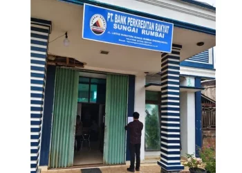 Petugas menempelkan lembar pemberitahuan pencabutan izin usaha PT BPR Sungai Rumbai, Kabupaten Dharmasraya, Sumatera Barat, Selasa (7/4/2026). (ANTARA/HO-OJK)