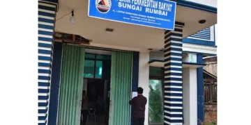 Petugas menempelkan lembar pemberitahuan pencabutan izin usaha PT BPR Sungai Rumbai, Kabupaten Dharmasraya, Sumatera Barat, Selasa (7/4/2026). (ANTARA/HO-OJK)
